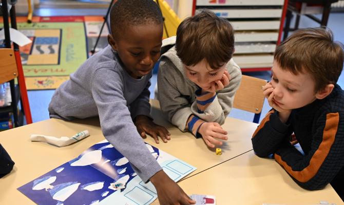 trois enfants qui jouent à un jeu éducatif